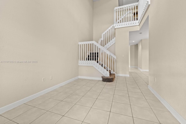 staircase featuring tile patterned flooring and a high ceiling