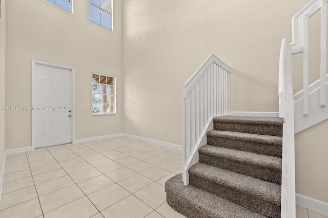 foyer entrance with light tile patterned flooring and a high ceiling