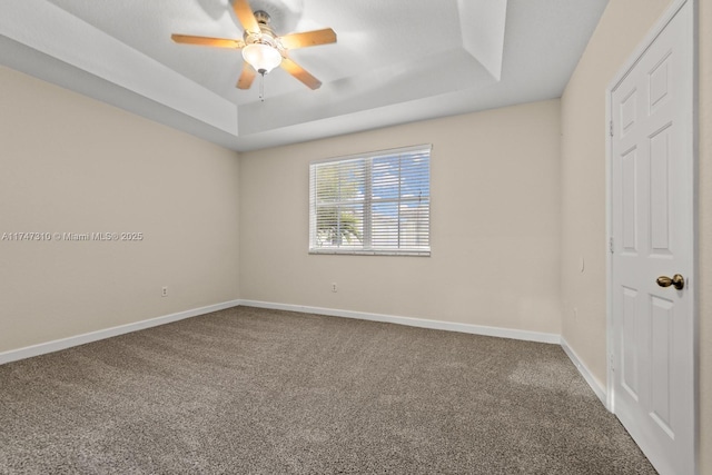 carpeted empty room with a tray ceiling and ceiling fan