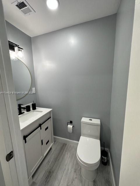 bathroom featuring toilet, vanity, and wood-type flooring