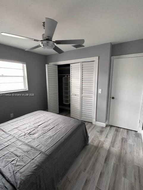 bedroom with a closet, hardwood / wood-style floors, and ceiling fan