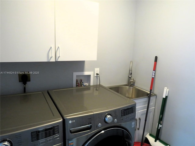 washroom with cabinets, washer and clothes dryer, and sink