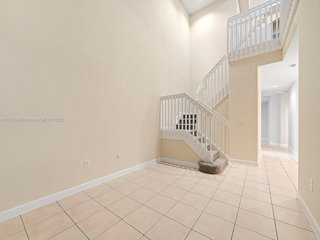 empty room featuring a towering ceiling and light tile patterned floors