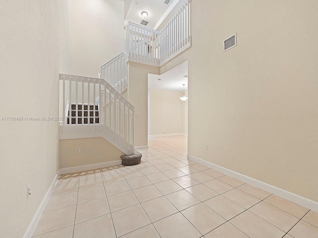 tiled spare room with a towering ceiling