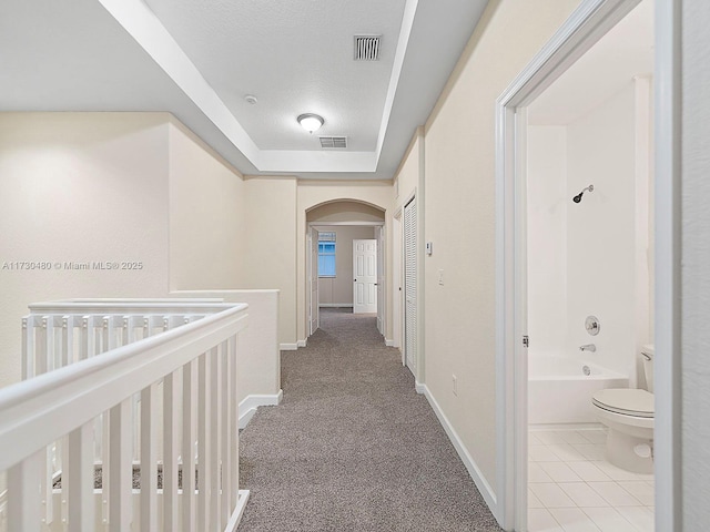 hallway featuring light carpet and a textured ceiling