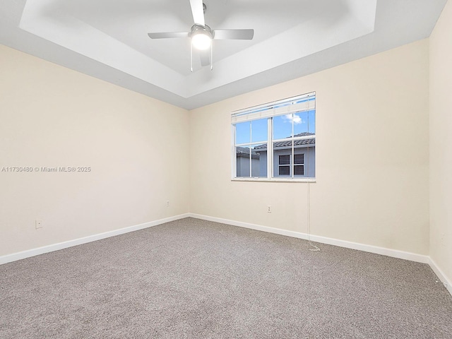 carpeted empty room with ceiling fan and a raised ceiling