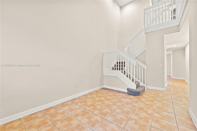 staircase featuring tile patterned flooring and a high ceiling