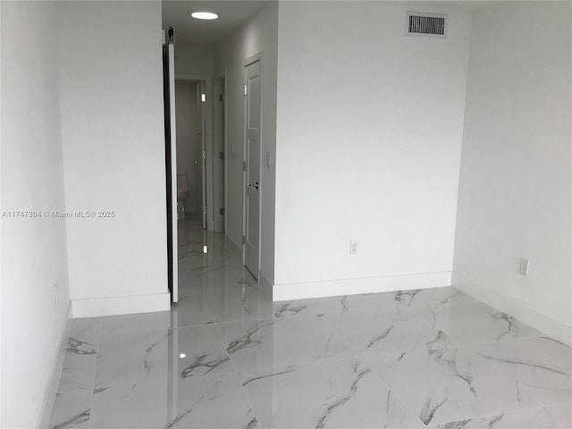 empty room with marble finish floor, visible vents, and baseboards