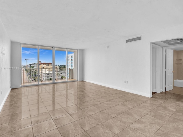 tiled spare room featuring expansive windows