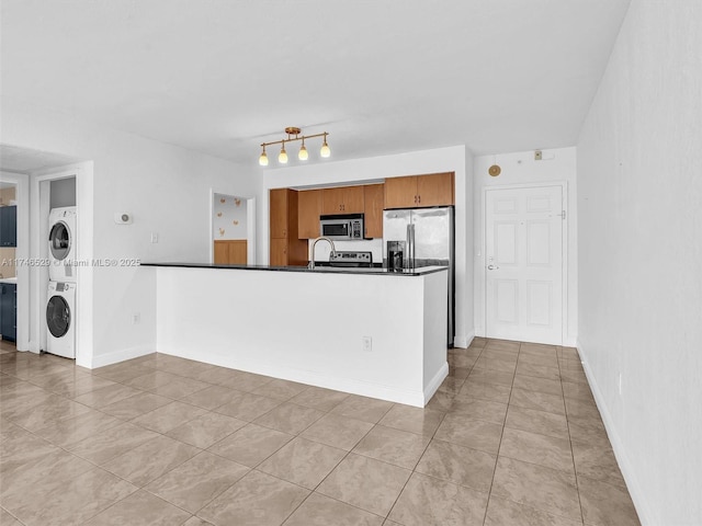 kitchen featuring kitchen peninsula, stacked washer / dryer, stainless steel appliances, and light tile patterned floors