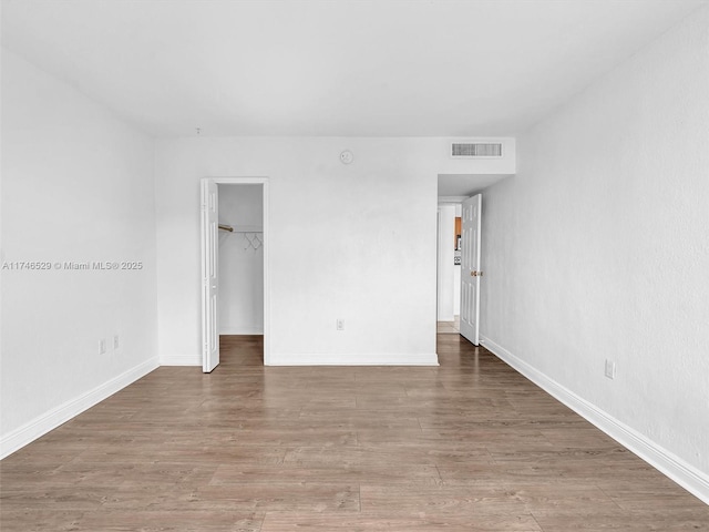 unfurnished bedroom featuring a spacious closet, a closet, and hardwood / wood-style floors