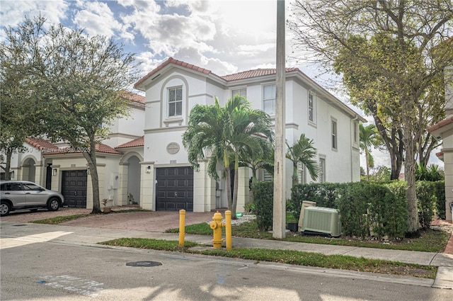 mediterranean / spanish home with a garage and central air condition unit