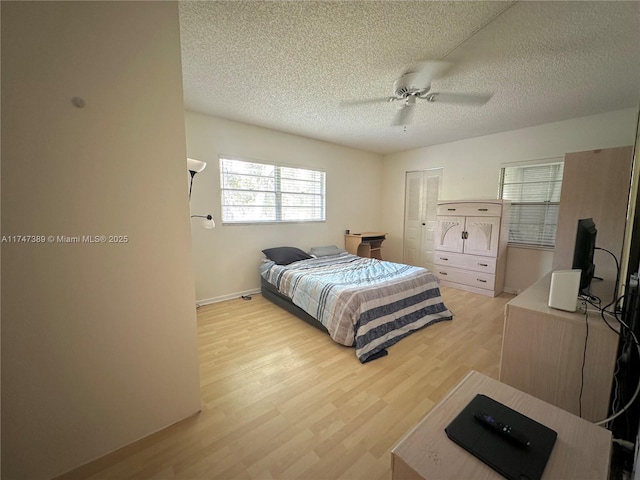 bedroom featuring ceiling fan, light wood-style flooring, and a textured ceiling