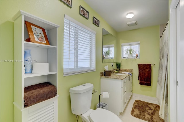 bathroom with tile patterned floors, toilet, vanity, and a healthy amount of sunlight