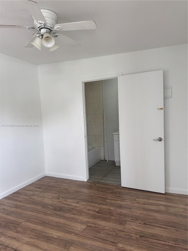 unfurnished bedroom with connected bathroom, baseboards, and wood finished floors