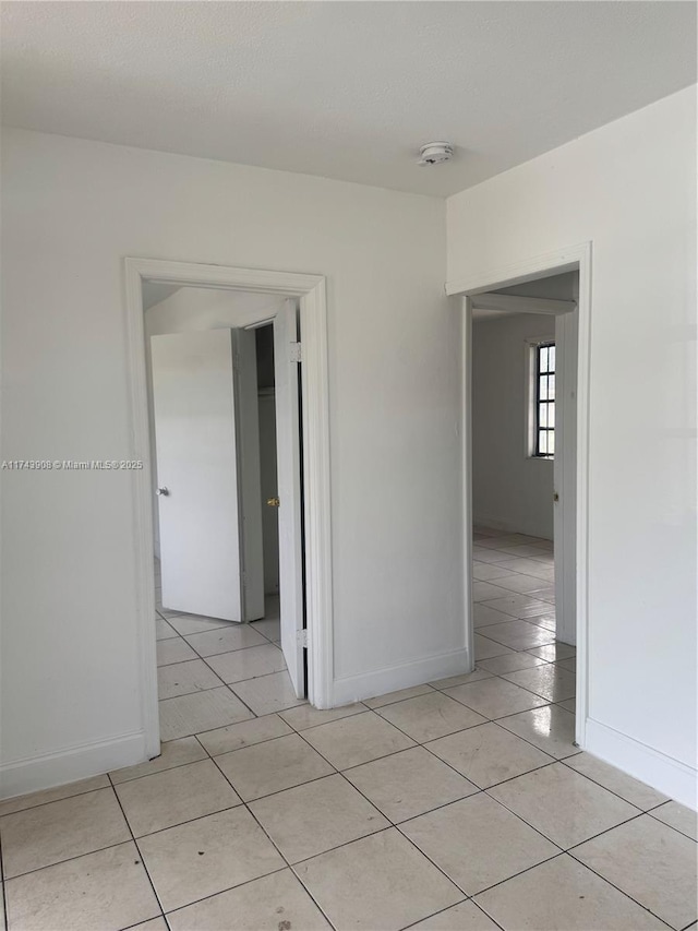 spare room with light tile patterned floors and baseboards