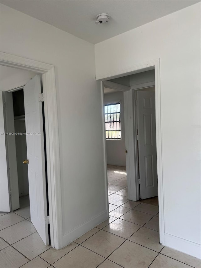 hall with light tile patterned flooring and baseboards