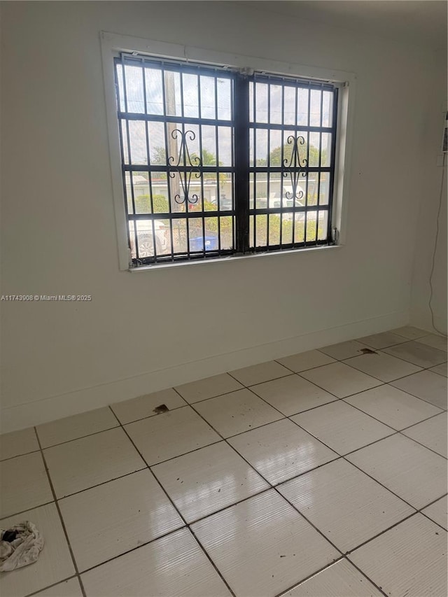 unfurnished room with light tile patterned floors and baseboards