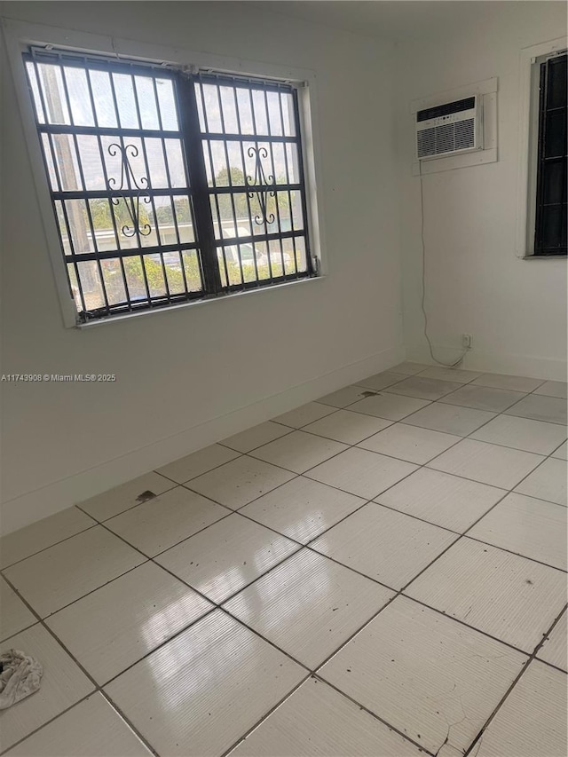 tiled empty room featuring baseboards and a wall mounted AC