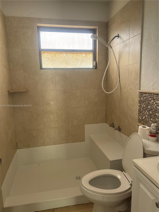 full bath featuring tile walls, toilet, tiled shower, and vanity