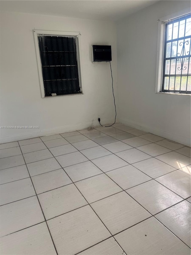 unfurnished room with light tile patterned floors and baseboards