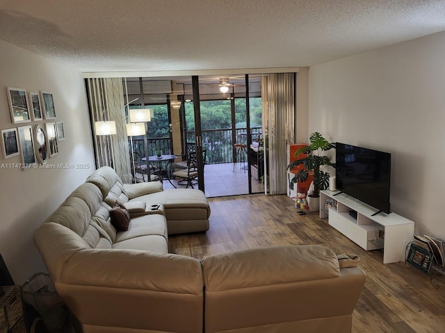 living room featuring a textured ceiling, a wall of windows, and hardwood / wood-style floors