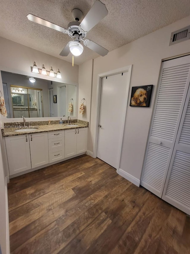 bathroom with a textured ceiling, vanity, ceiling fan, and wood-type flooring