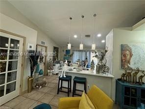 kitchen with hanging light fixtures, vaulted ceiling, a breakfast bar, and light tile patterned floors