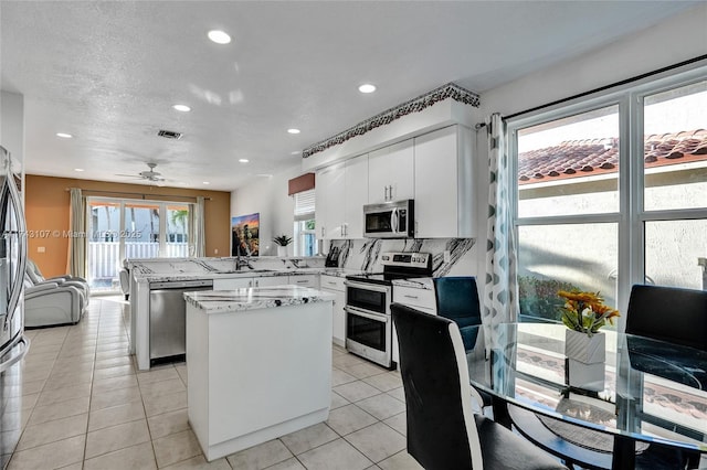 1588 SW 191st Ave, Pembroke Pines, FL 33029 - kitchen featuring a peninsula, white cabinets, a kitchen island, recessed lighting, and appliances with stainless steel finishes