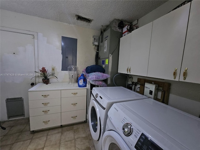 clothes washing area featuring washing machine and dryer, electric panel, light tile patterned flooring, a textured ceiling, and cabinets