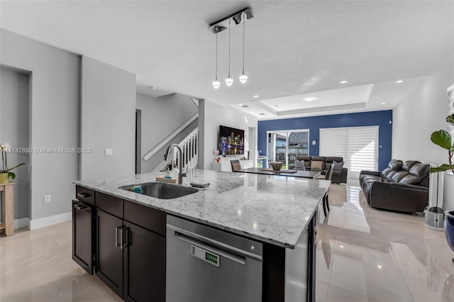 kitchen featuring dishwasher, an island with sink, open floor plan, pendant lighting, and a sink