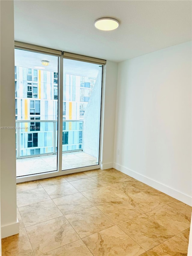 spare room featuring a wall of windows, a healthy amount of sunlight, and light tile patterned floors