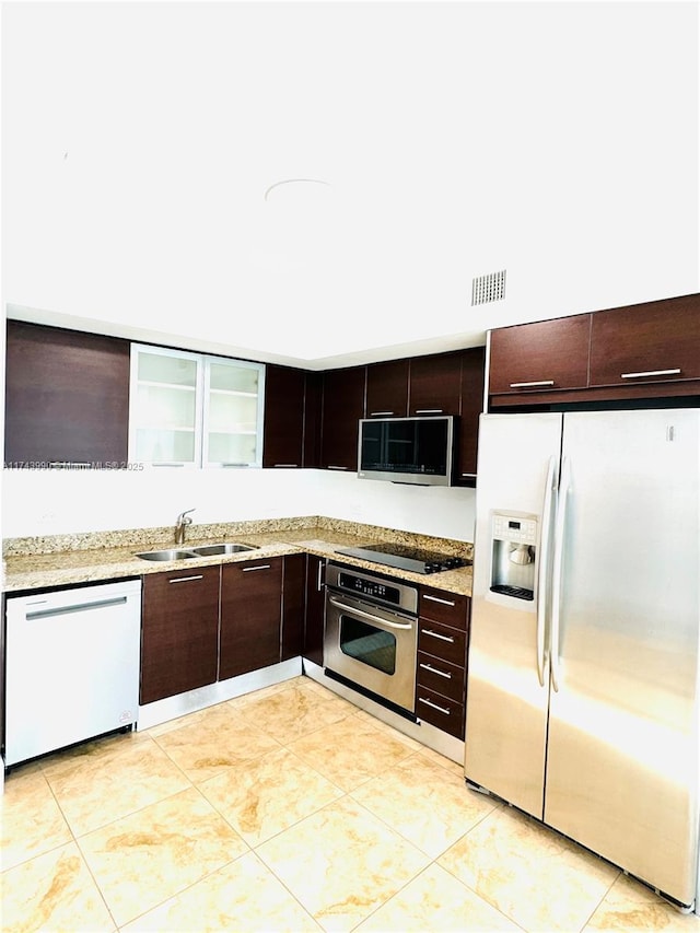 kitchen featuring appliances with stainless steel finishes, light tile patterned flooring, sink, and dark brown cabinets