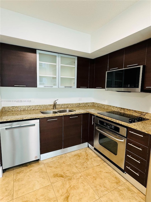 kitchen with sink, dark brown cabinets, stainless steel appliances, and light stone counters