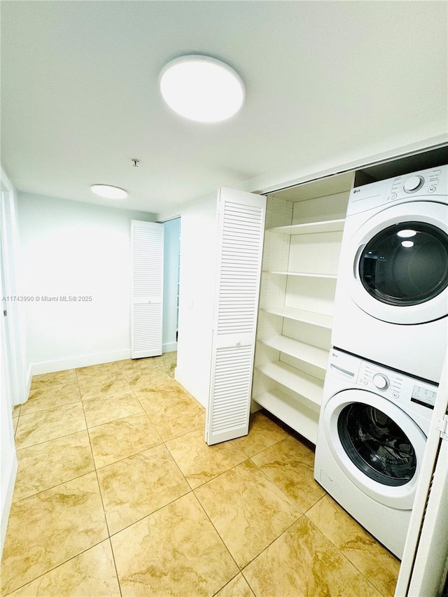 washroom with light tile patterned flooring and stacked washing maching and dryer