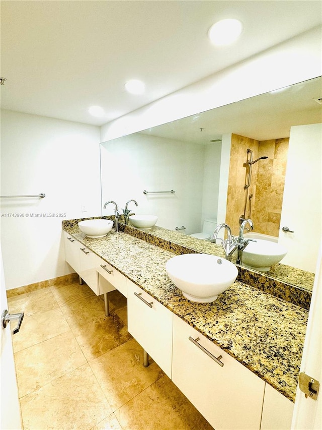 bathroom with vanity, tile patterned flooring, toilet, and tiled shower