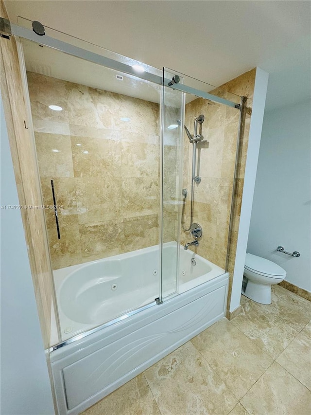 bathroom featuring toilet and bath / shower combo with glass door