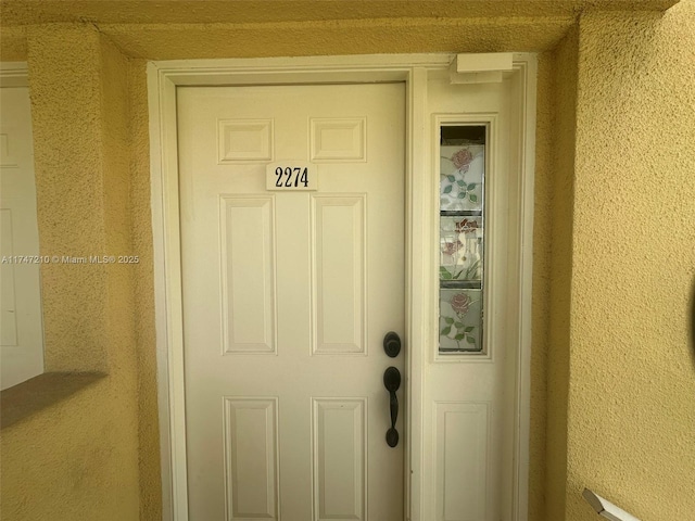 doorway to property featuring stucco siding