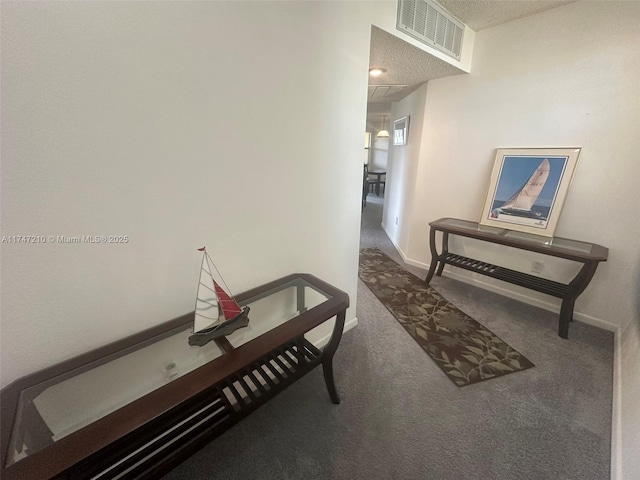 hallway featuring baseboards, visible vents, and carpet