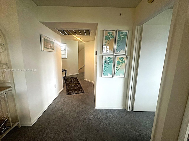 hallway with carpet floors, visible vents, and baseboards