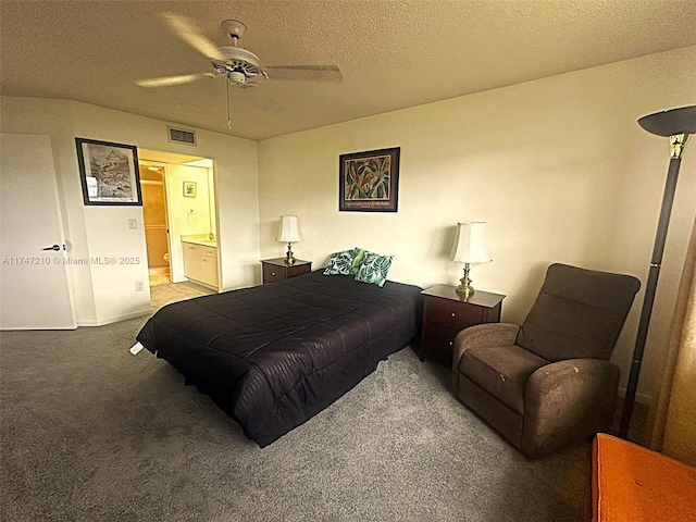 carpeted bedroom with ensuite bath, visible vents, a textured ceiling, and a ceiling fan