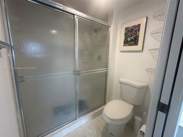 bathroom featuring a shower stall, toilet, and tile patterned floors