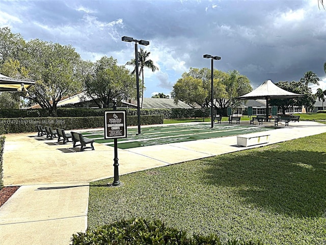 view of property's community featuring a yard and shuffleboard