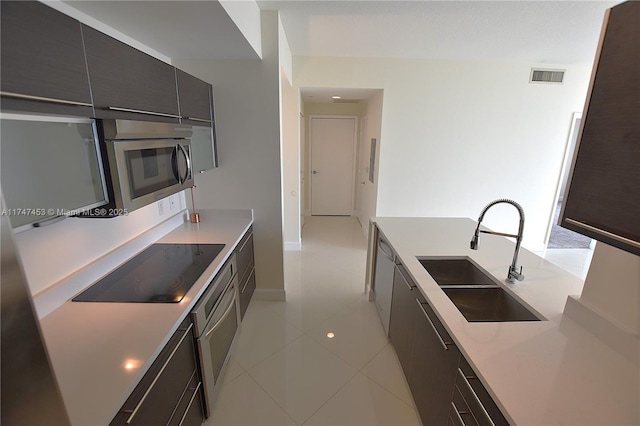 kitchen with sink, black electric stovetop, wall oven, and light tile patterned floors