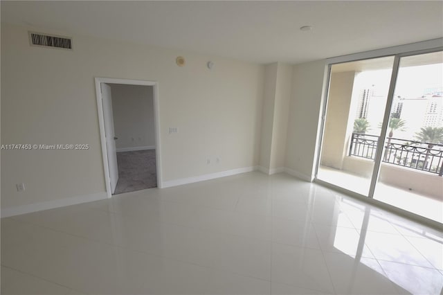 tiled spare room featuring a wall of windows