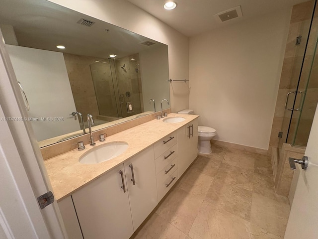 bathroom featuring toilet, a shower with shower door, and vanity