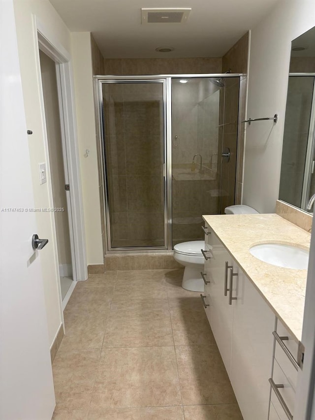 bathroom with toilet, tile patterned floors, a shower with shower door, and vanity