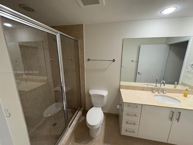 bathroom with tile patterned floors, toilet, vanity, and a shower with door