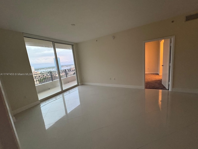 unfurnished room with expansive windows and light tile patterned floors