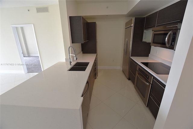 kitchen featuring sink, light tile patterned flooring, stainless steel appliances, and dark brown cabinetry